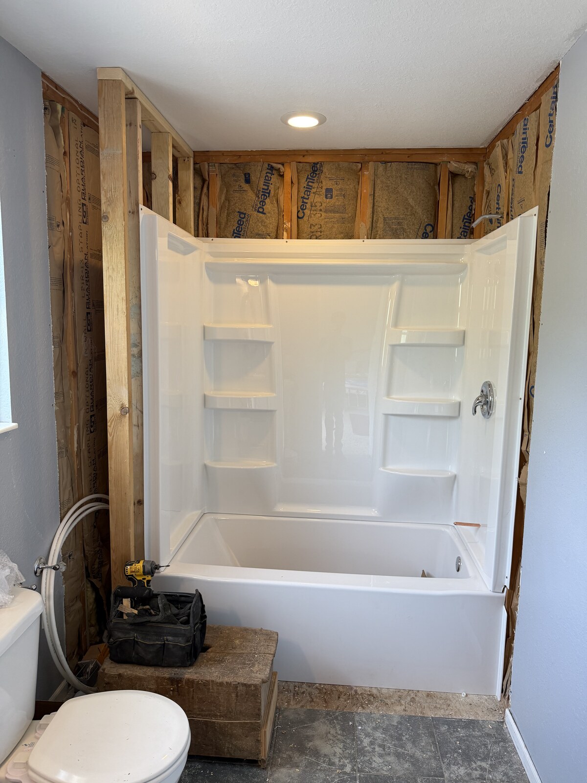Tub and surround fitted while the adjacent framing remains exposed.