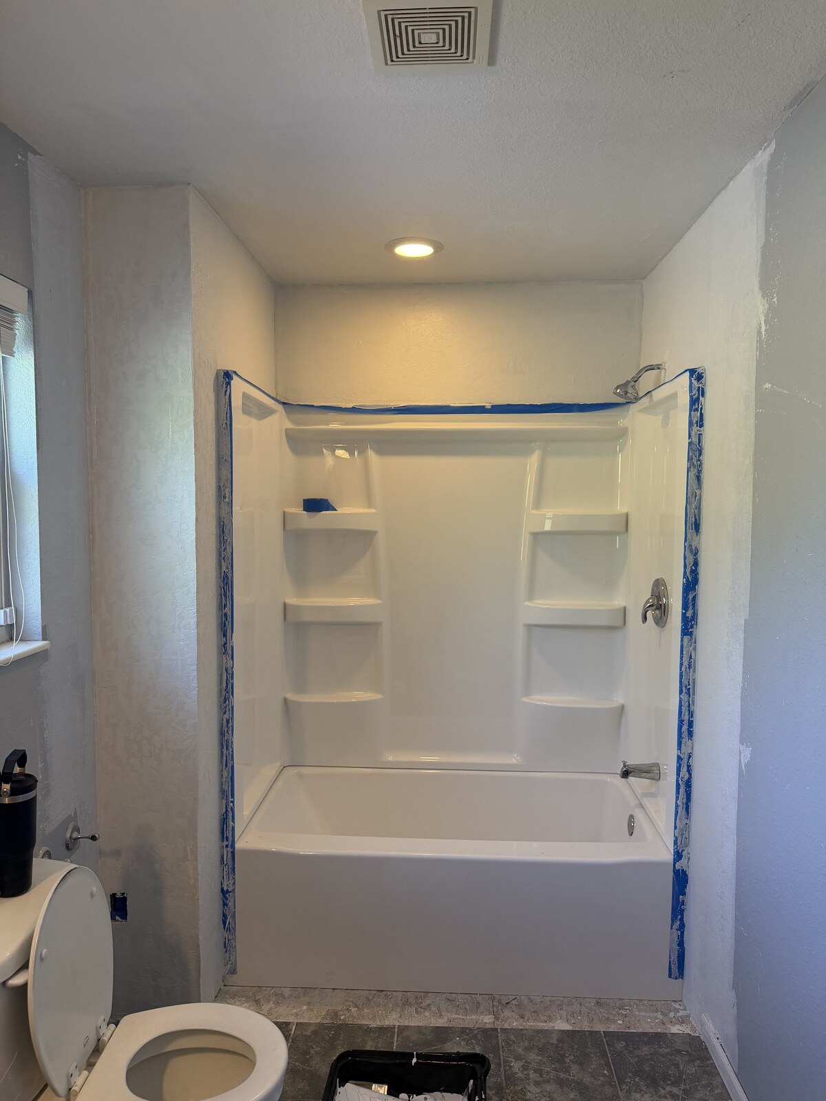 Wall finishing around the new surround, with edges masked.