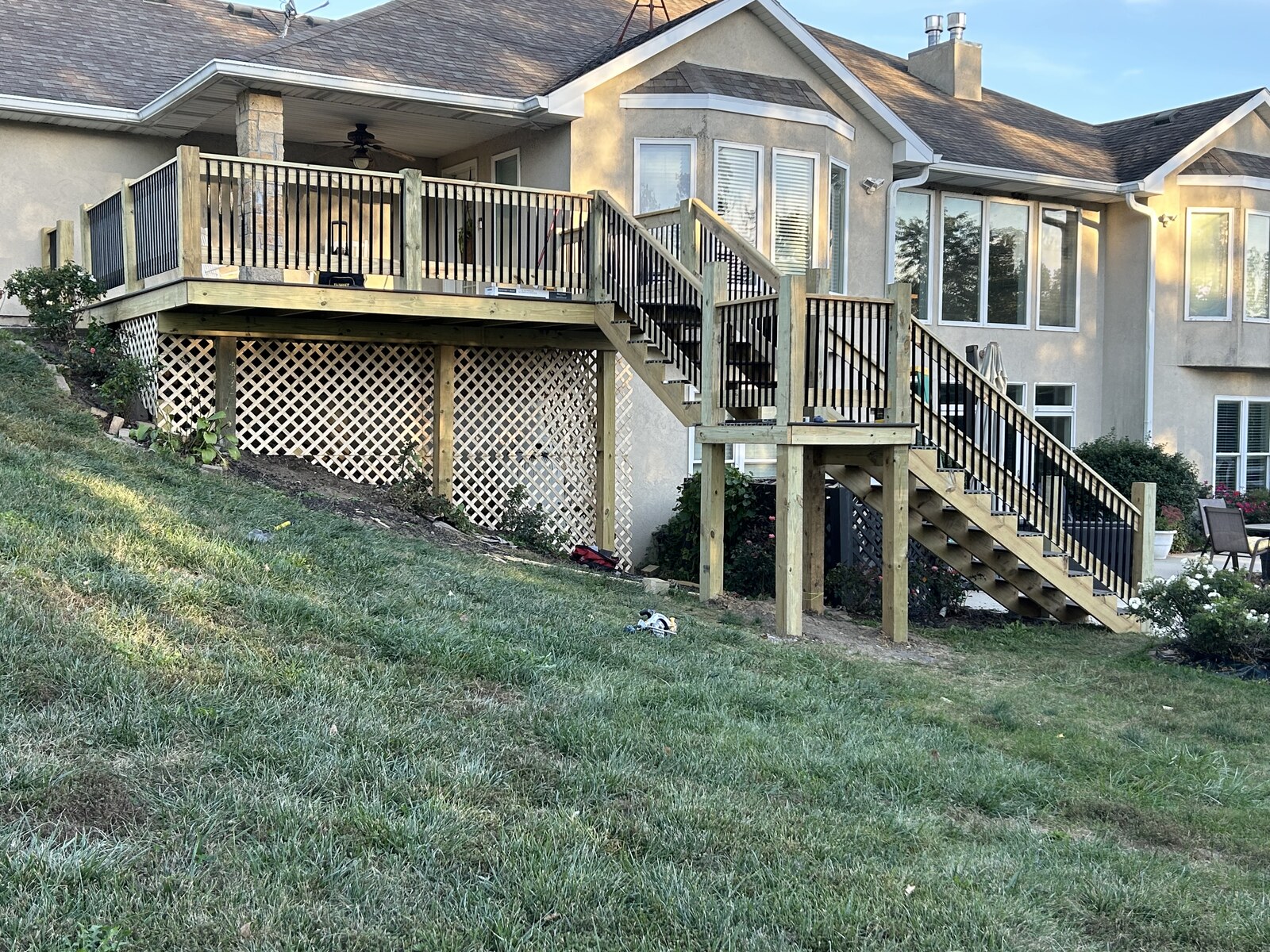 Two-flight stairs with black-baluster railings and lattice below.