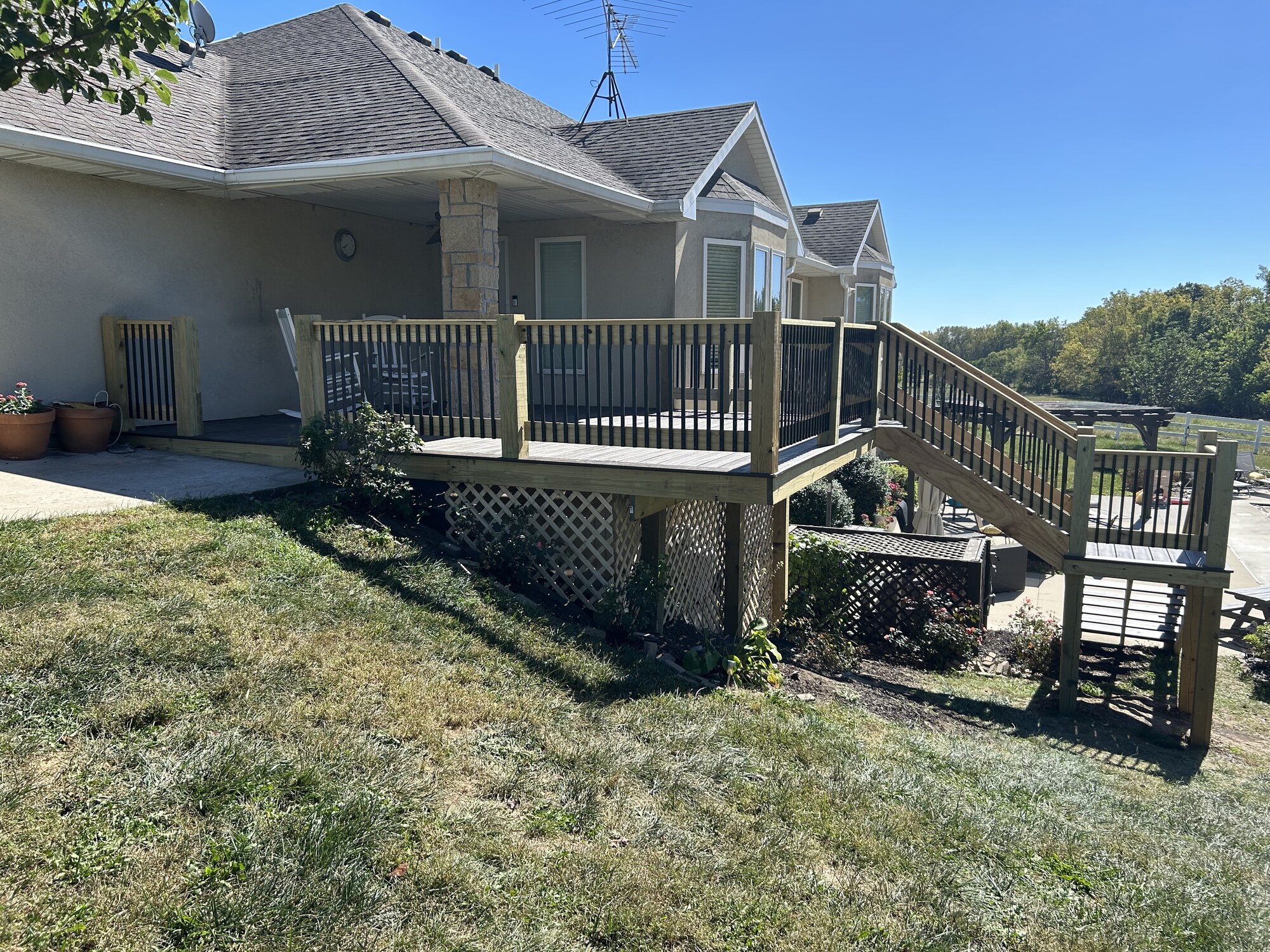 Finished deck with railings, two stair flights and an intermediate landing, viewed from the opposite side.
