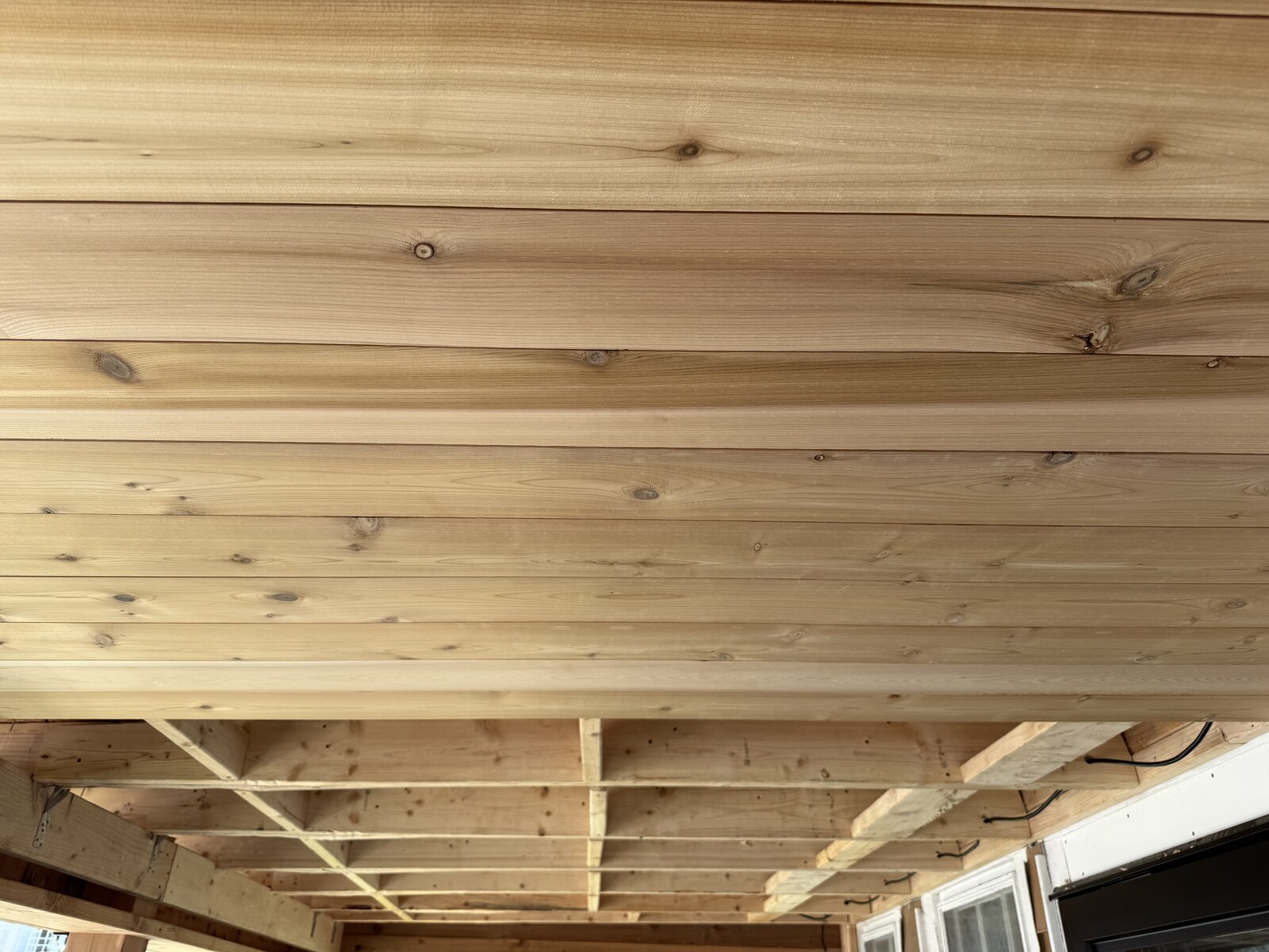 Ceiling boards meet the exposed roof framing during installation.