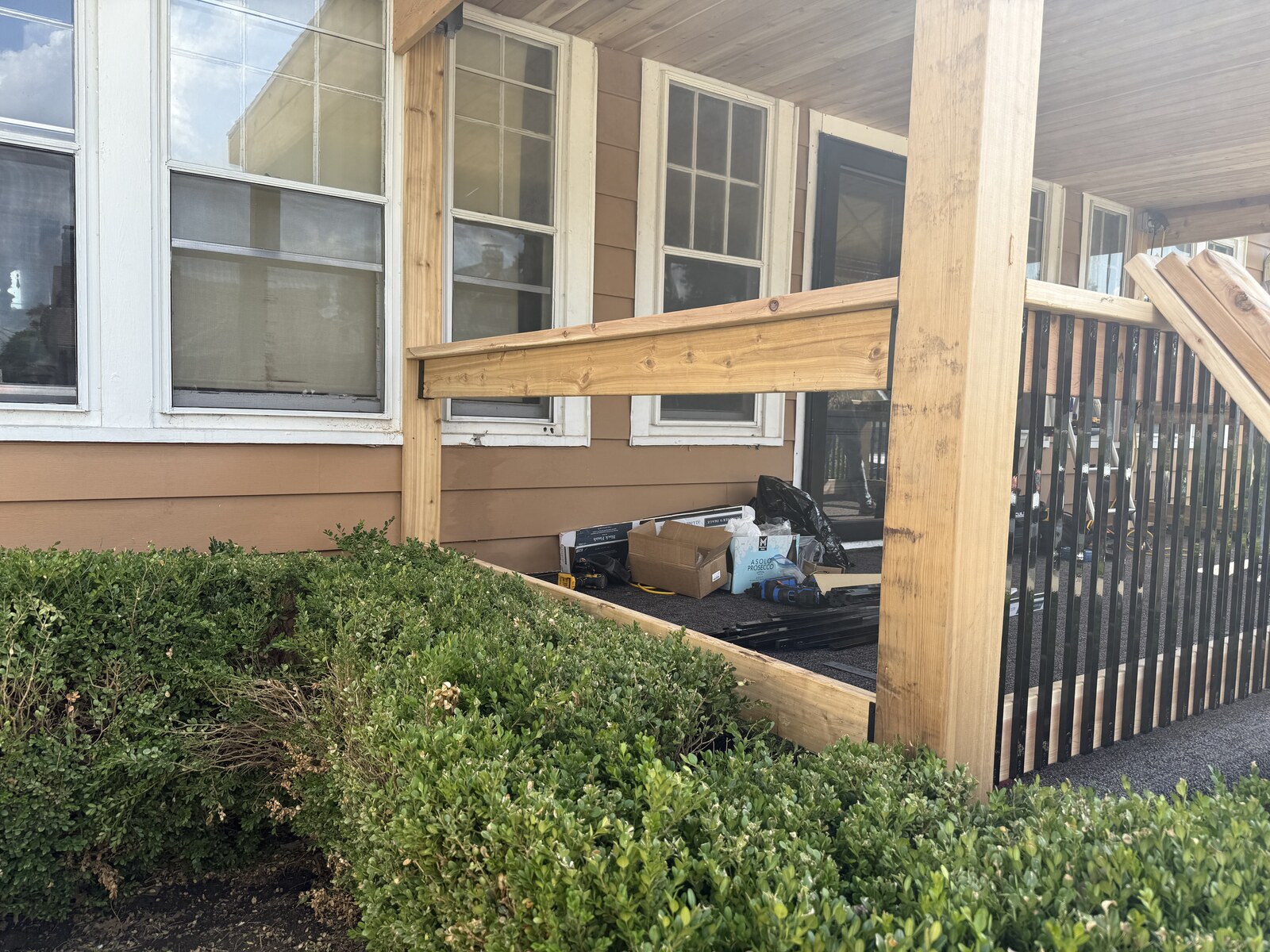 Wood rails and black balusters assembled between porch posts.
